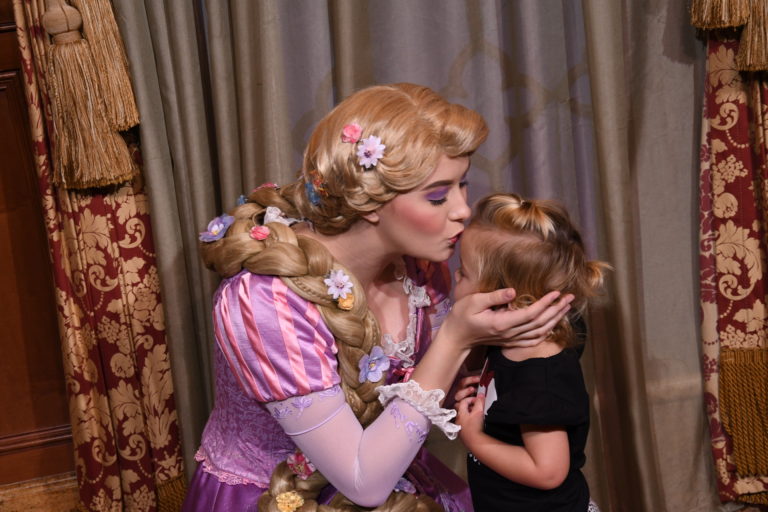 a woman in a pink dress kissing a little girl.