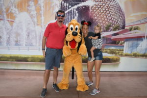 a man, woman and two children posing with pluto the dog.